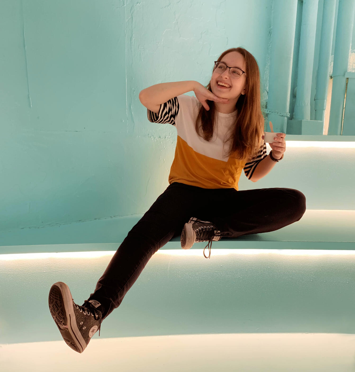 A photo of myself sitting on some stairs, posing with my hand under my chin and my leg extended